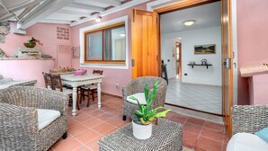 A cozy patio area with wicker furniture, a dining table, and a potted plant. - Panoramic Holiday Apartment "Isuledda" with Sea View, Shared Pool & Air Conditioning (San Teodoro)
