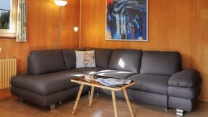 Una sala de estar moderna con un sofá gris, una mesa de centro de madera, una lámpara de pie y un cuadro en la pared.