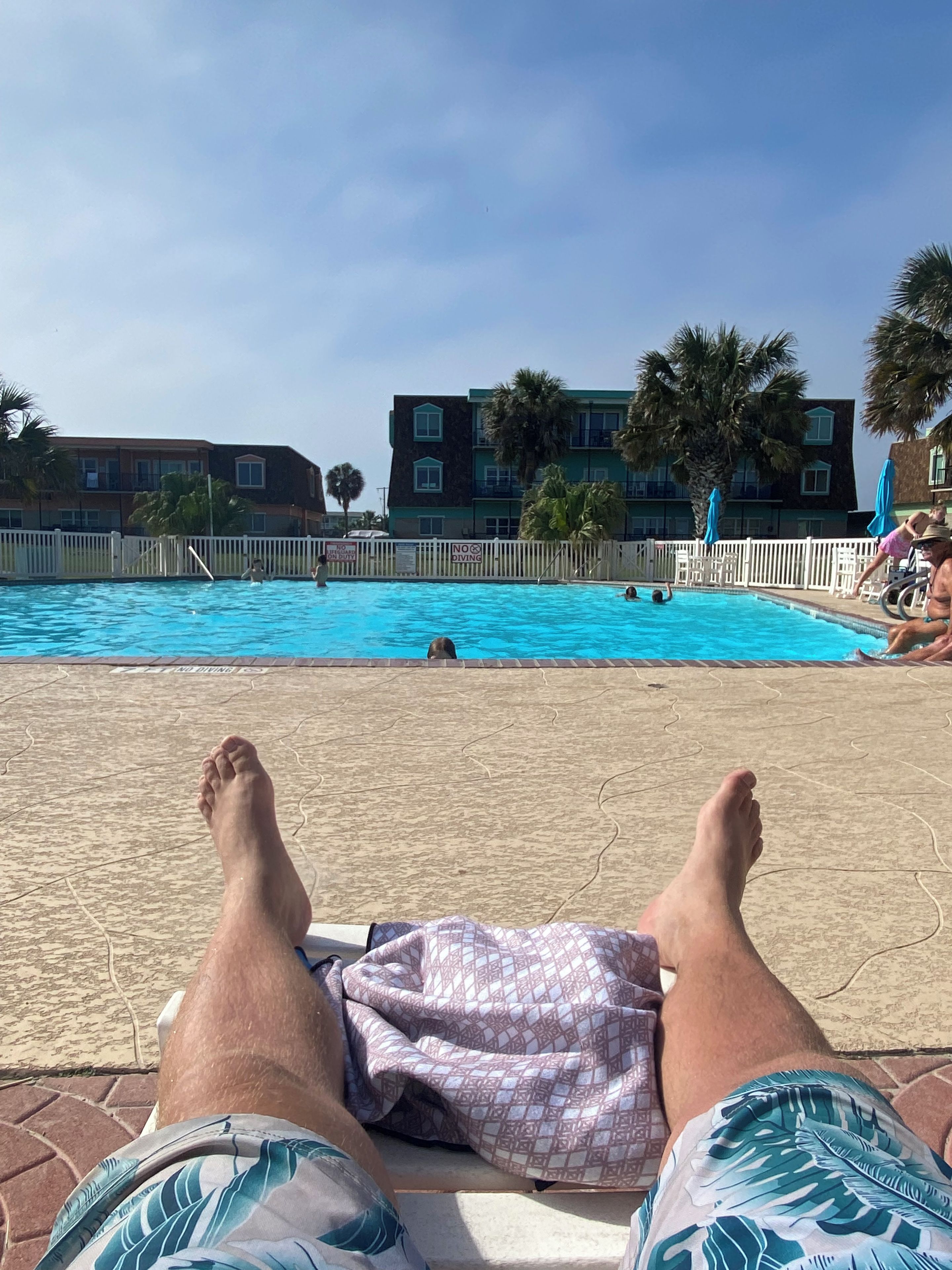 Vista a la piscina bajo un cielo despejado, con edificios al fondo.