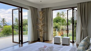 A spacious bedroom with a large bed, two bedside tables, and a view of a lush garden through large windows. - Villa Tango with private Pool, Koh Yao Noi  (Ko Yao Noi)