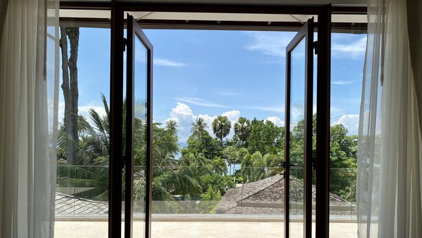 A room with a large sliding glass door leading to a balcony with a view of palm trees and a clear sky. - Villa Tango with private Pool, Koh Yao Noi  (Ko Yao Noi)