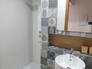 Bathroom features a minimalist design with geometric and botanical patterns on the walls, a central sink, and a mirror above.