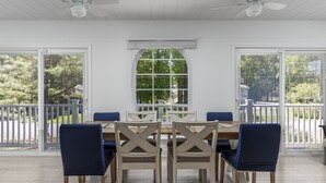 Een eethoek met een houten tafel en stoelen, grote ramen en uitzicht op het landschap.