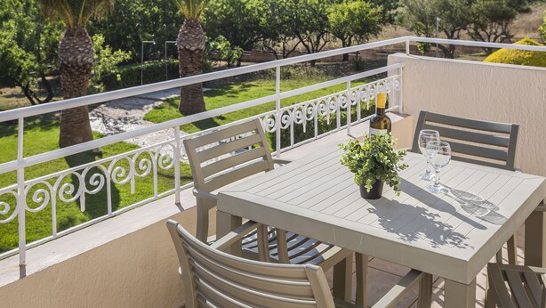 Ein Balkon mit Tisch, Stühlen, einem Blumentopf und einer Weinflasche.