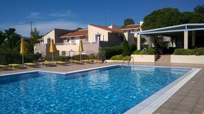 Una piscina al aire libre de temporada, sombrillas