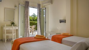 Ein Hotelzimmer mit zwei Betten, einem Schreibtisch, einem Stuhl und einer Schiebetür zum Außenbereich.