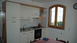 A kitchen with white cabinets, a stove, and a window. - Vacation House in S. Maria di Leuca 900m from the sea (CASTRIGNANO DEL CAPO)