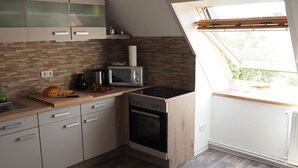 A modern kitchen with a stone backsplash, wooden cabinets, a microwave, and an oven. - Recreation and activity in the countryside with picturesque landscapes (Nahrendorf)