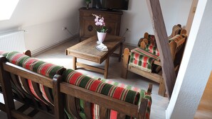 A cozy loft bedroom with a sloped ceiling, a wooden dresser, a television, and a striped chair. - Recreation and activity in the countryside with picturesque landscapes (Nahrendorf)