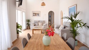 Ein modernes Wohnzimmer mit einem Holzespeisetisch, grauen Sofas und einem großen Fenster.