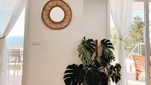Ein Wohnzimmer mit einer großen Kübelpflanze, einem an der Wand befestigten Fernseher und einer runden Wanddekoration.