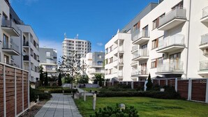 A modern residential building with balconies, a paved walkway, and a well-maintained lawn. - Apartment "Küstenperle"; top floor apartment with large terrace (Świnoujście)