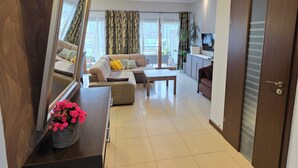 A modern living room with a sofa, coffee table, and a TV. There is a mirror on the wall and a door with a sliding mechanism. - Apartment "Küstenperle"; top floor apartment with large terrace (Świnoujście)