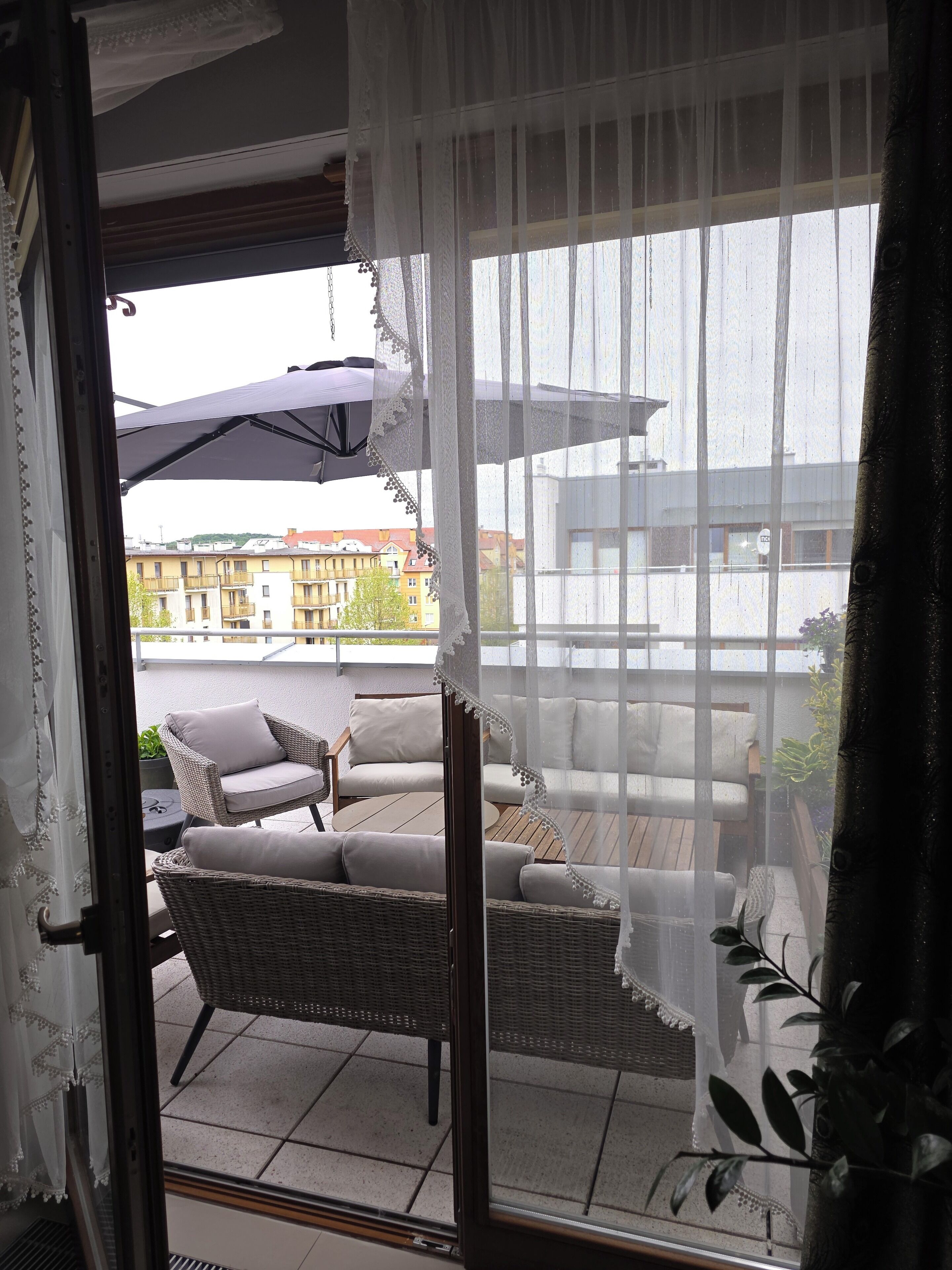Un balcon doté de meubles en osier et offrant une vue sur les immeubles.
