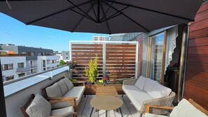 A rooftop patio with wicker furniture, a round table, and a large umbrella. - Apartment "Küstenperle"; top floor apartment with large terrace (Świnoujście)