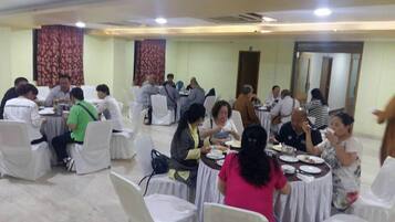 A banquet hall with round tables covered in white tablecloths, arranged in rows.