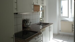 A modern kitchen with white cabinets, a granite countertop, and a built-in oven. There is a window providing natural light and a view of the outside. - Large bright apartment with garage Centre Quimper (Quimper)