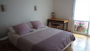 A bedroom with a bed, a desk, and a window with a view of flowers. - Large bright apartment with garage Centre Quimper (Quimper)