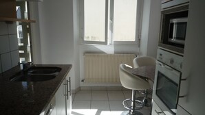 A kitchen with a window, a radiator, a sink, a microwave, and a chair. - Large bright apartment with garage Centre Quimper (Quimper)