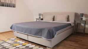 A neatly arranged bedroom with a bed, two bedside tables, and a patterned rug. - Vacation apartment time out! In the middle of the Palatinate Forest. (Erfweiler)