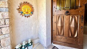 A wooden door with a metal grid, a decorative sun with a face, and a stone wall with a stone staircase. - Calm hilltop villa with pool EV Charge Valbonne Walks (Opio)