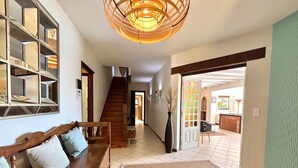 A spacious hallway with a wooden bench, a staircase, and a large open door leading to another room. - Calm hilltop villa with pool EV Charge Valbonne Walks (Opio)