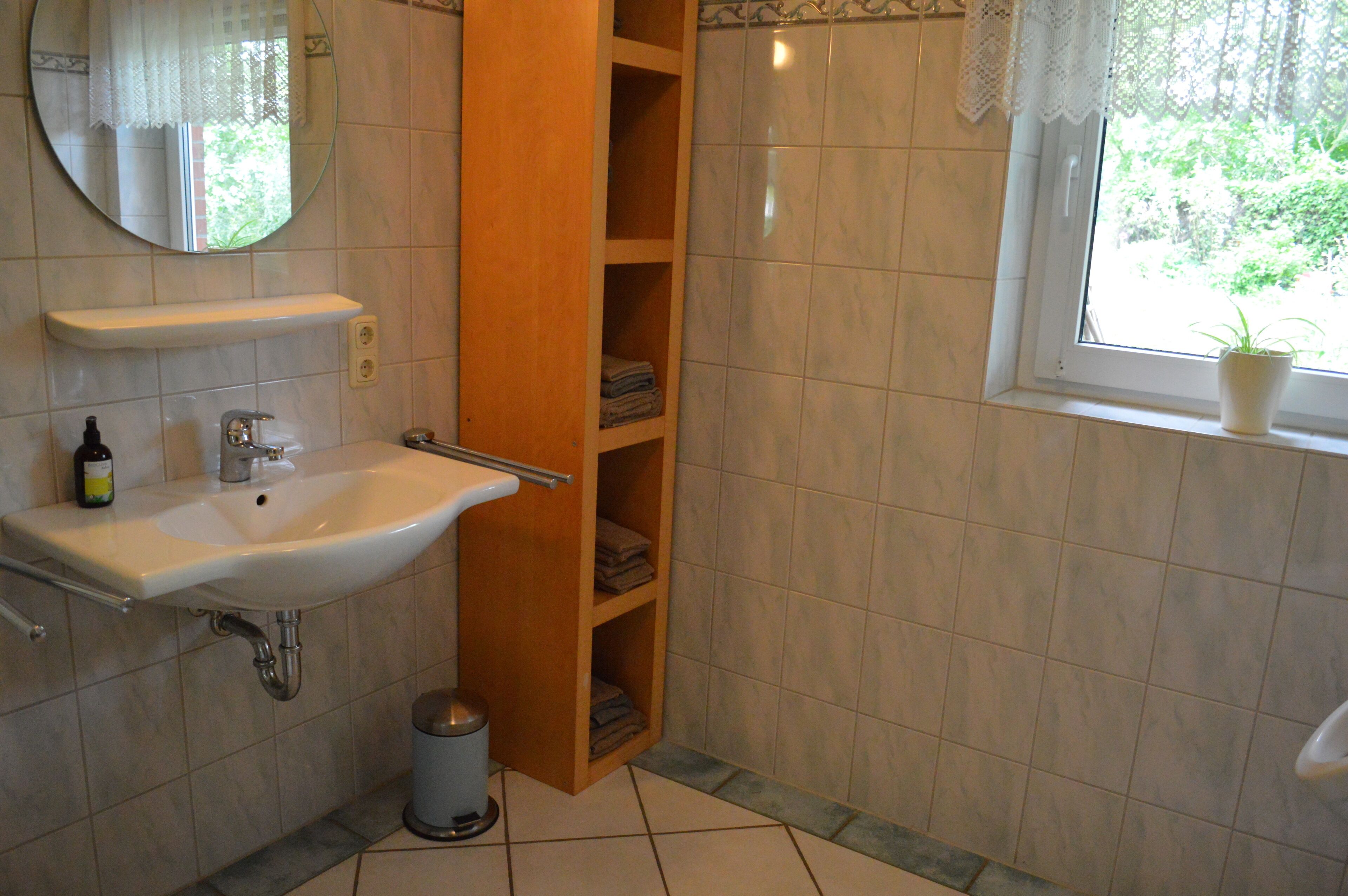 Een badkamer met een wastafel, spiegel en planken.