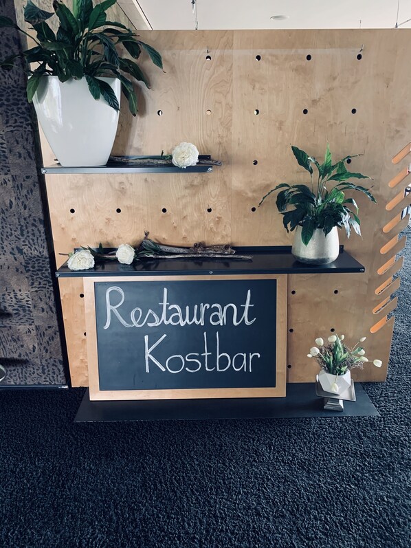 Una tabla de madera con un letrero de pizarra que dice "Restaurant Kostbar".