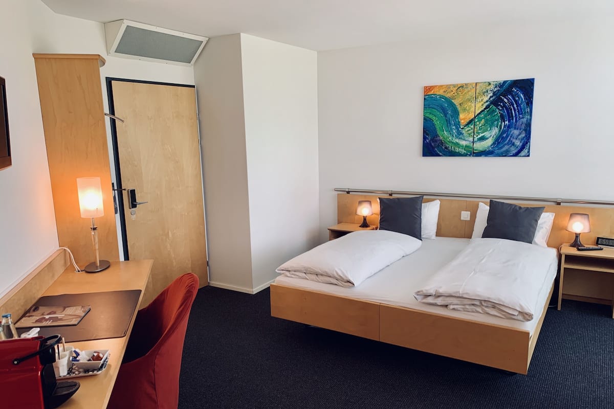 Une chambre d’hôtel avec un lit, un bureau, une chaise et une œuvre d’art au mur.