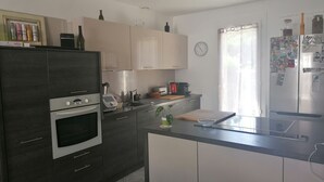 Una cucina moderna con mobili scuri, forno integrato, macchina da caffè e finestra con tende.