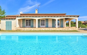 A Mediterranean-style villa with a swimming pool, featuring a tiled roof, stucco walls, and a covered patio area.