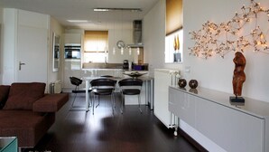 A modern apartment with a dining area, kitchen, and living room. - Porta Isola - Villa Water (Stevensweert)