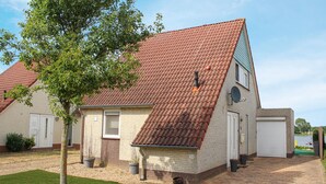 A two-story house with a red-tiled roof, a small front porch, and a brick pathway leading to the entrance. - Porta Isola - Villa Water (Stevensweert)