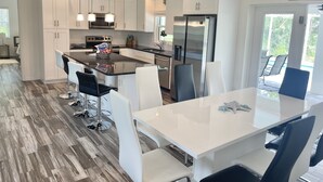 Una cocina moderna con armarios blancos, electrodomésticos de acero inoxidable y una isla central con taburetes de bar.