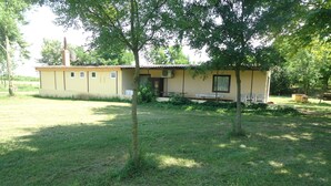 A single-story building with a flat roof, a chimney, and a small porch area with a bench.