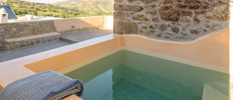A stone wall with a pool and a towel on a ledge.