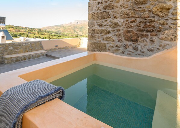 A stone wall with a pool and a towel on a ledge.