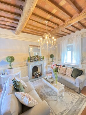 A living room with a fireplace, a chandelier, a sofa set, and a coffee table.