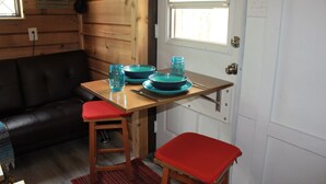 Une cuisine compacte aux murs en bois, avec un canapé en cuir noir et une petite table à manger accompagnée de deux tabourets.