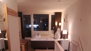 Une chambre d’hôtel avec un lit, une table de chevet, une lampe et une vue sur l’extérieur.