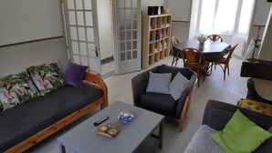 A living room with a sofa, armchairs, a coffee table, and a dining area with a table and chairs. - Character house for 6 people (Plestin-les-Grèves)