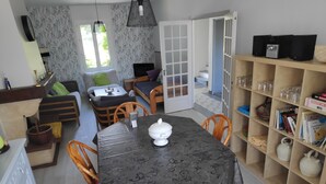 A cozy living area with a sofa, a dining table with chairs, a bookshelf, and a door leading to another room. - Character house for 6 people (Plestin-les-Grèves)