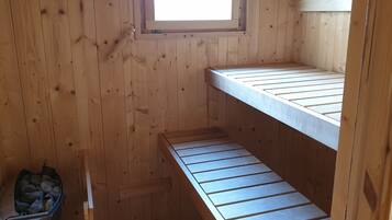 A wooden cabin with bunk beds, a small window, and a fireplace.