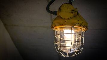 A yellow lantern with a metal wire cage, hanging from a ceiling.