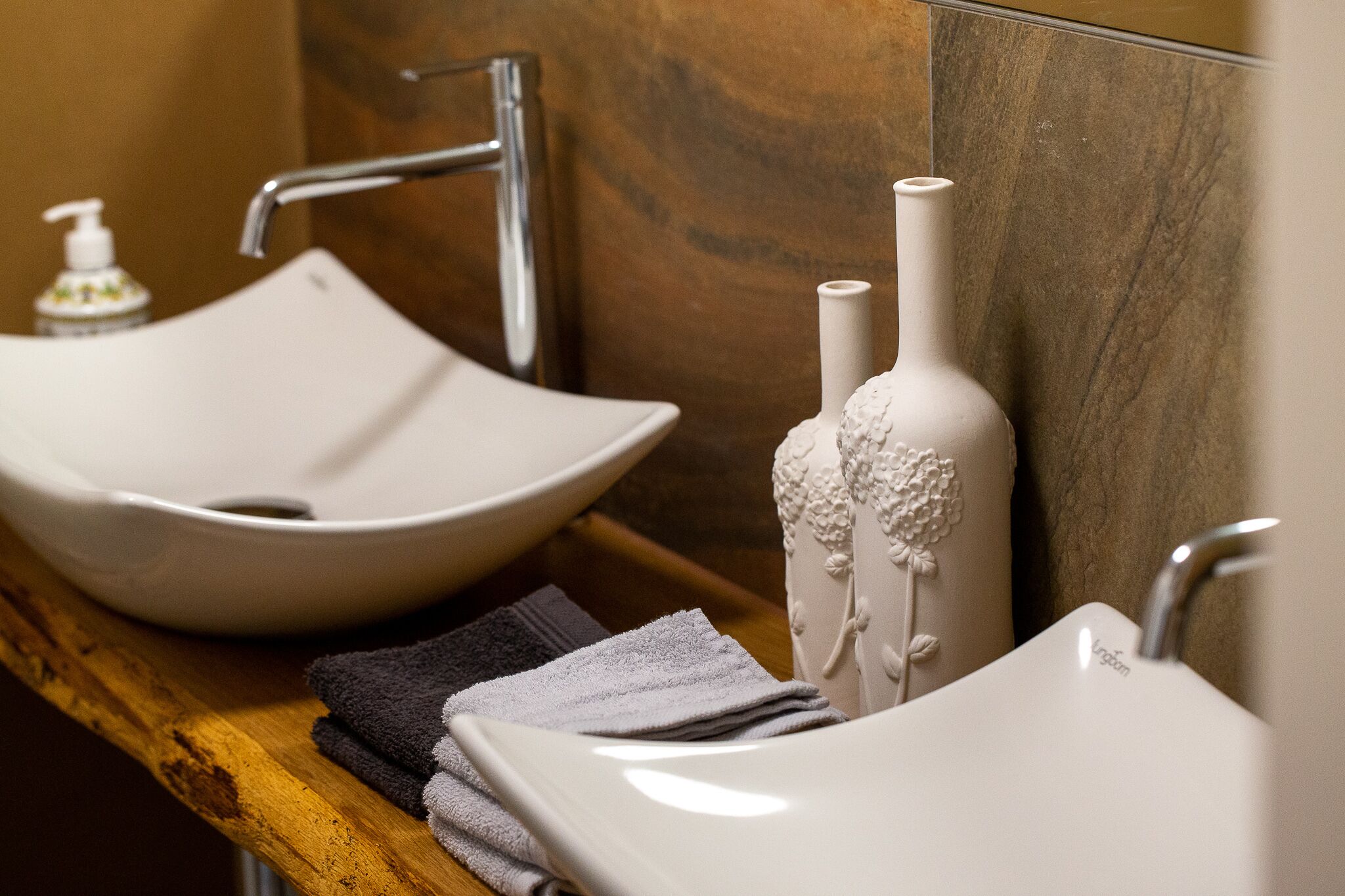 A bathroom with a white vessel sink, a modern faucet, and a decorative vase with floral patterns.