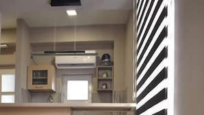 Una cocina moderna con taburetes de madera, una silla gris y una ventana con persianas blanco y negro.