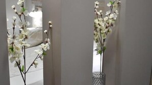 Un pasillo con dos arreglos idénticos de orquídeas blancas en contenedores metálicos.
