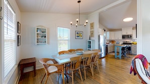 Una cocina amplia con suelo de madera, una isla central y una zona de comedor con sillas de mimbre.