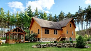 A wooden cabin with a stone foundation, a covered porch, and a stone retaining wall.