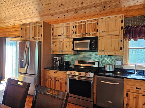 A kitchen with wooden cabinets, stainless steel appliances, and a window with a view.